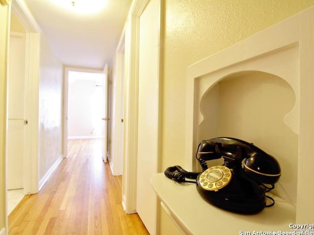 corridor with light hardwood / wood-style floors and a textured ceiling