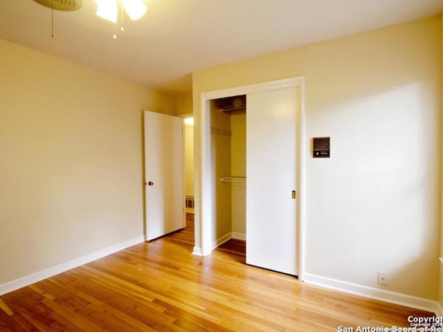 unfurnished bedroom with ceiling fan, a closet, and hardwood / wood-style flooring