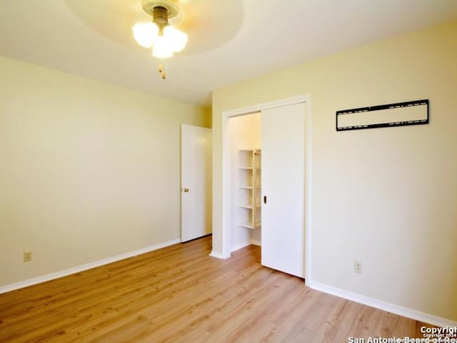 unfurnished bedroom featuring ceiling fan, a closet, and light wood-type flooring