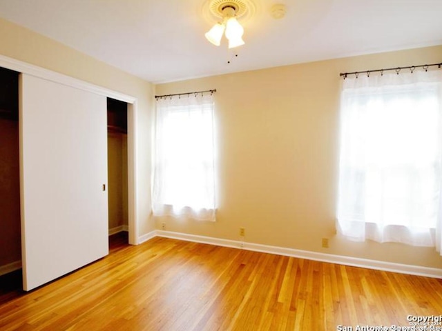 unfurnished bedroom featuring hardwood / wood-style flooring, ceiling fan, and a closet