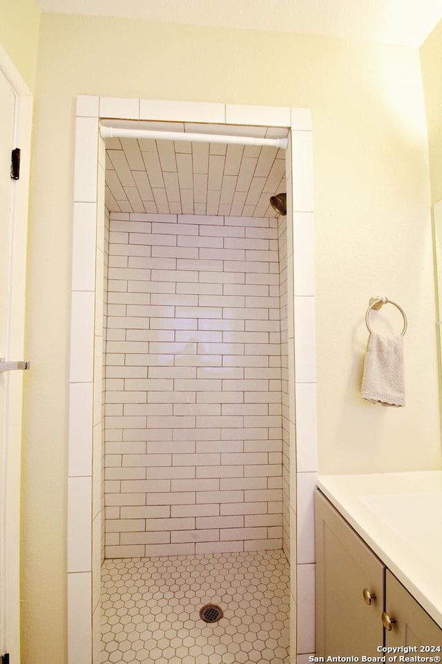 bathroom with tiled shower and vanity