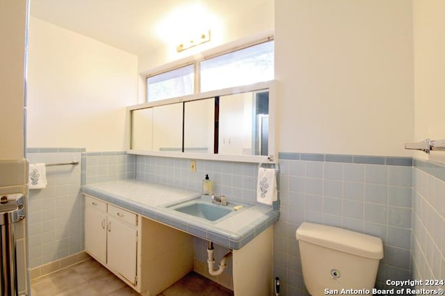 bathroom featuring tile patterned flooring, toilet, tile walls, and sink