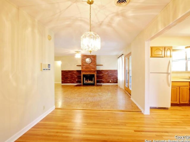 corridor with a chandelier, wood-type flooring, and brick wall