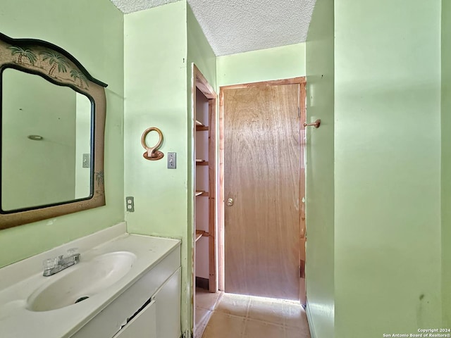 bathroom with tile patterned flooring, vanity, and a textured ceiling