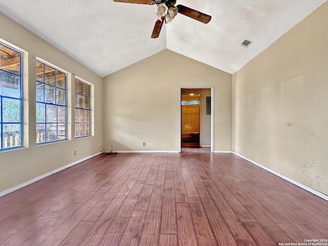 empty room featuring wood-type flooring, a textured ceiling, and vaulted ceiling