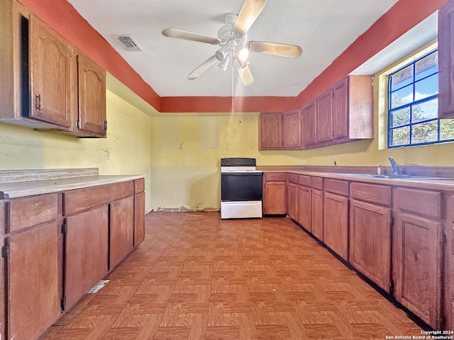 kitchen with a textured ceiling, white range oven, ceiling fan, sink, and light parquet flooring