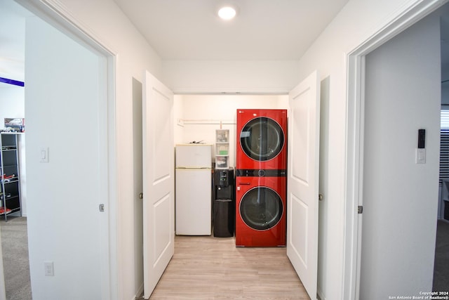 clothes washing area with stacked washing maching and dryer and light wood-type flooring