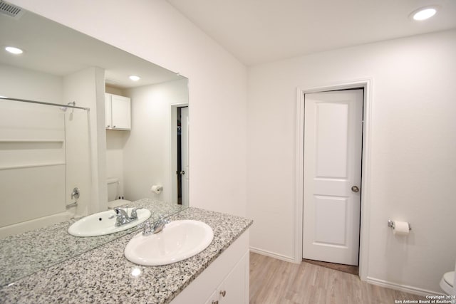 full bathroom featuring hardwood / wood-style flooring, vanity,  shower combination, and toilet