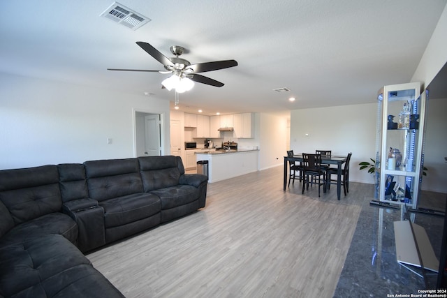 living room featuring ceiling fan, light hardwood / wood-style floors, and a textured ceiling