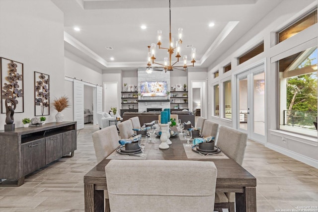 dining room with french doors, a raised ceiling, a chandelier, light hardwood / wood-style floors, and a fireplace