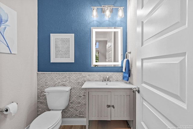 bathroom featuring vanity, hardwood / wood-style flooring, toilet, and tile walls