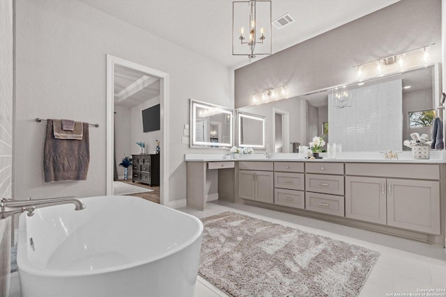 bathroom with tile patterned flooring, vanity, a tub, and an inviting chandelier