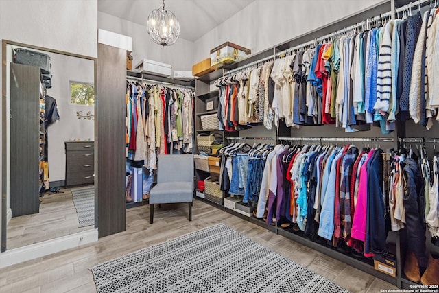 walk in closet with wood-type flooring and an inviting chandelier