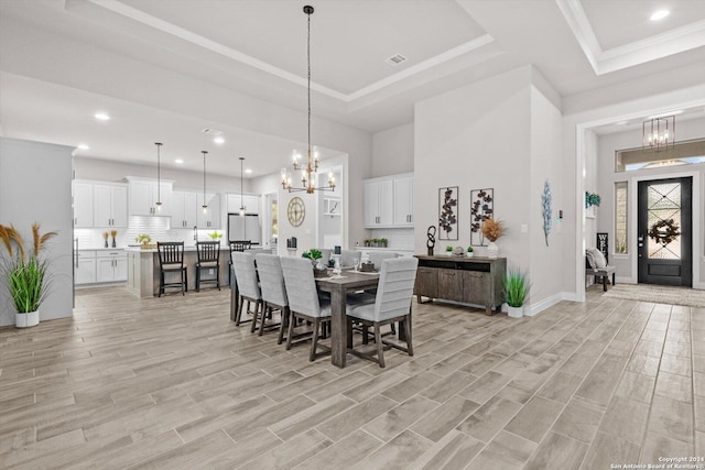 dining area featuring a chandelier, light hardwood / wood-style floors, and a tray ceiling