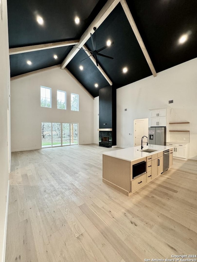 kitchen featuring white cabinetry, light hardwood / wood-style flooring, high vaulted ceiling, a spacious island, and appliances with stainless steel finishes