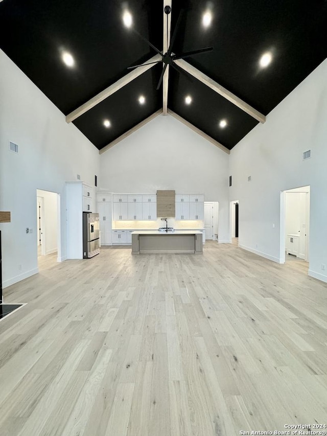 unfurnished living room featuring beam ceiling, light hardwood / wood-style flooring, and high vaulted ceiling