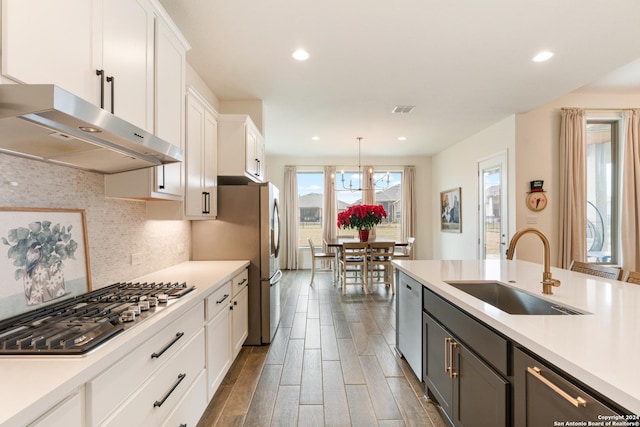 kitchen featuring sink, dark wood-type flooring, hanging light fixtures, backsplash, and white cabinets