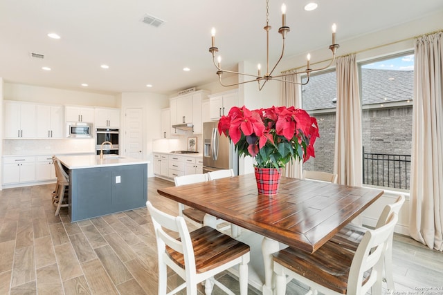 dining area featuring light hardwood / wood-style floors, sink, and an inviting chandelier