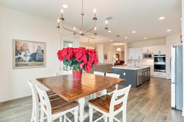 dining room with light wood-type flooring, sink, and an inviting chandelier