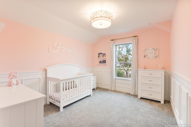 carpeted bedroom featuring a nursery area and lofted ceiling