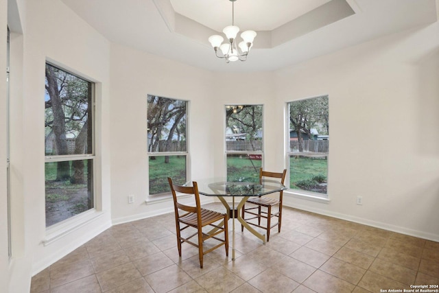 dining space featuring a notable chandelier, light tile patterned floors, and a tray ceiling