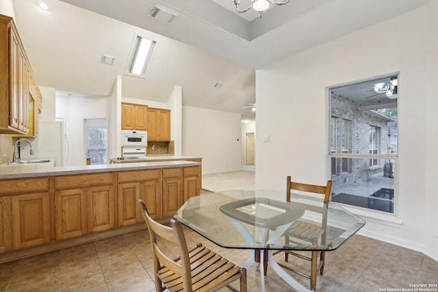 tiled dining room featuring lofted ceiling, a notable chandelier, and sink