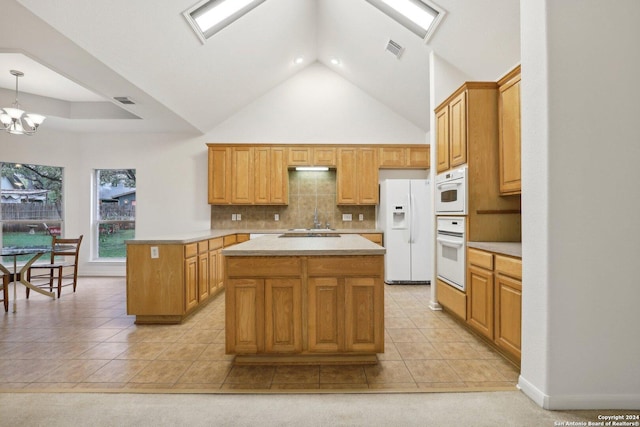 kitchen with white appliances, high vaulted ceiling, a center island, hanging light fixtures, and light tile patterned flooring