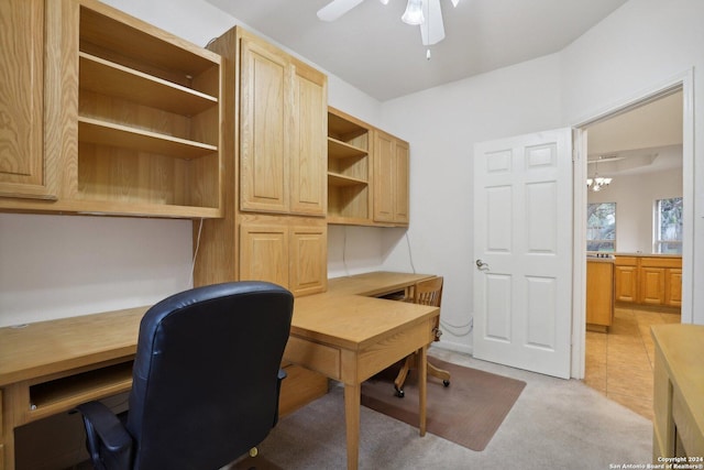 carpeted office space featuring ceiling fan with notable chandelier