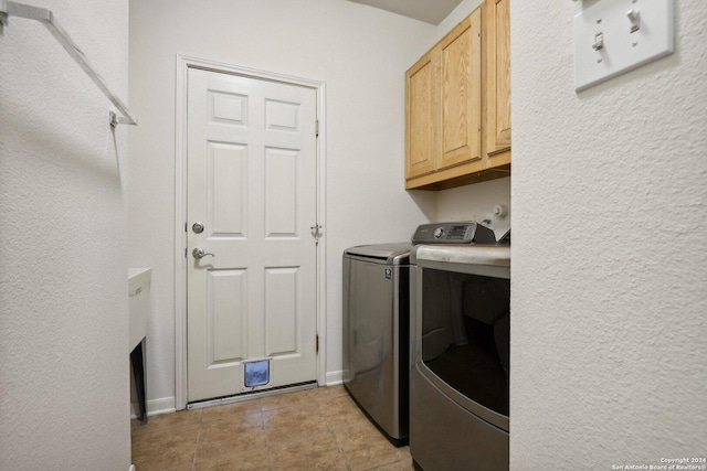 laundry area with washer and clothes dryer, cabinets, and light tile patterned floors