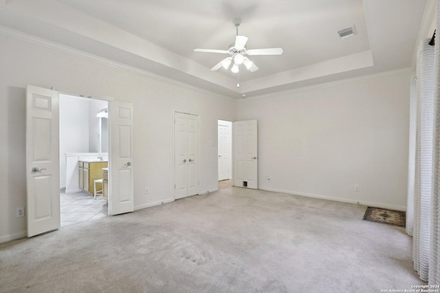 unfurnished bedroom featuring light carpet, ornamental molding, a raised ceiling, ceiling fan, and connected bathroom