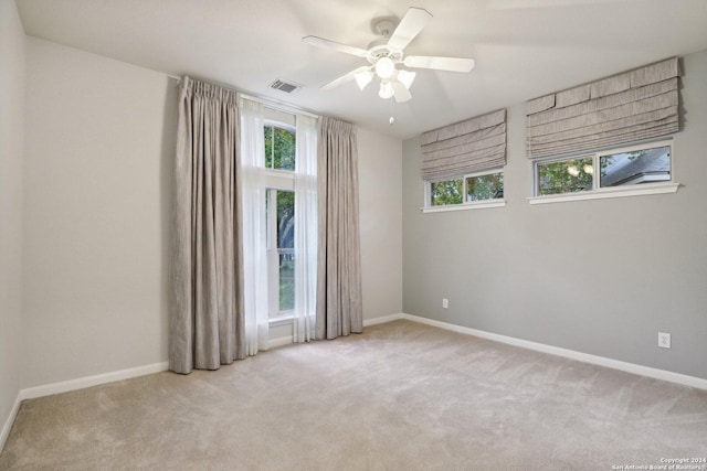 carpeted spare room with a wealth of natural light and ceiling fan