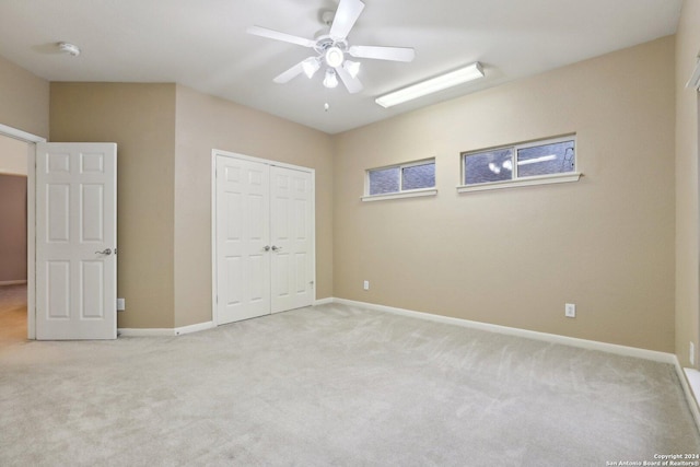 unfurnished bedroom featuring light carpet, a closet, and ceiling fan