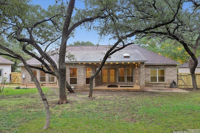 back of house featuring french doors, a patio area, and a lawn