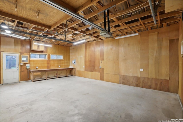 garage featuring a garage door opener and wooden walls