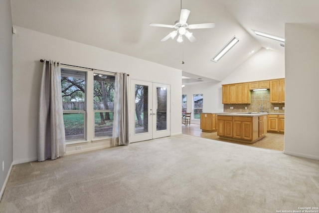 unfurnished living room with a skylight, ceiling fan, french doors, and light carpet