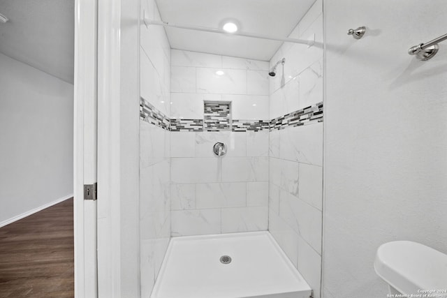 bathroom featuring tiled shower, hardwood / wood-style flooring, and toilet