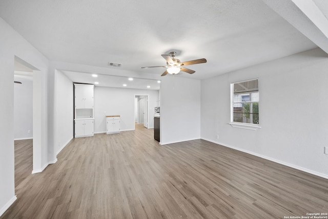 unfurnished living room with a textured ceiling, light hardwood / wood-style floors, and ceiling fan