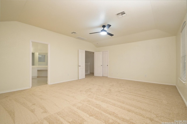 unfurnished bedroom with ceiling fan, lofted ceiling, light carpet, and connected bathroom