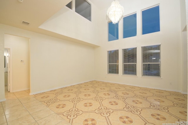 tiled spare room featuring a towering ceiling and an inviting chandelier