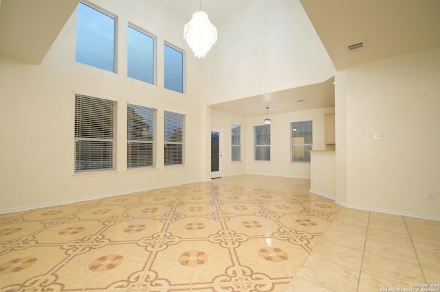 unfurnished living room featuring a high ceiling, an inviting chandelier, and light tile patterned floors