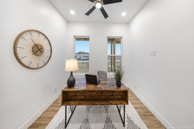 home office with light hardwood / wood-style floors and ceiling fan