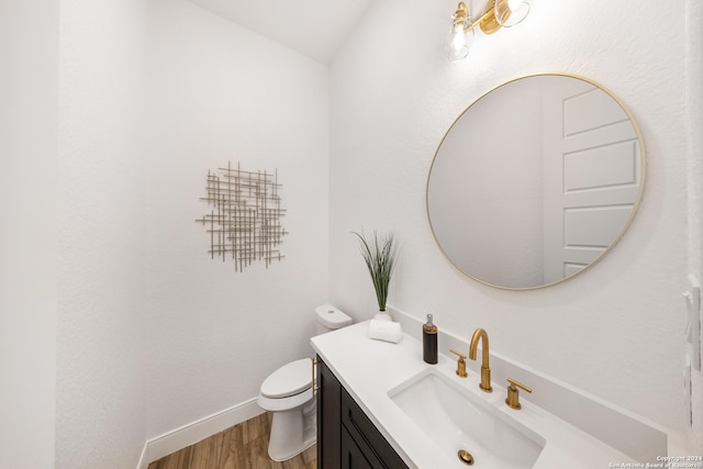 bathroom with hardwood / wood-style floors, vanity, toilet, and lofted ceiling