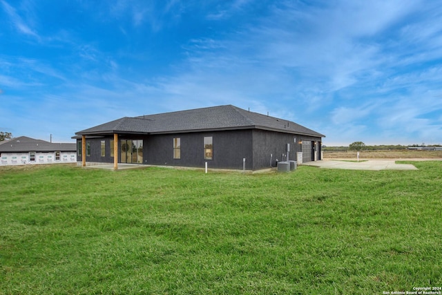 rear view of house featuring a lawn and central AC unit