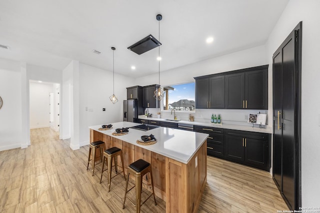 kitchen with a center island, stainless steel fridge with ice dispenser, sink, and light hardwood / wood-style flooring