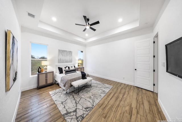 bedroom with a tray ceiling, ceiling fan, and hardwood / wood-style floors