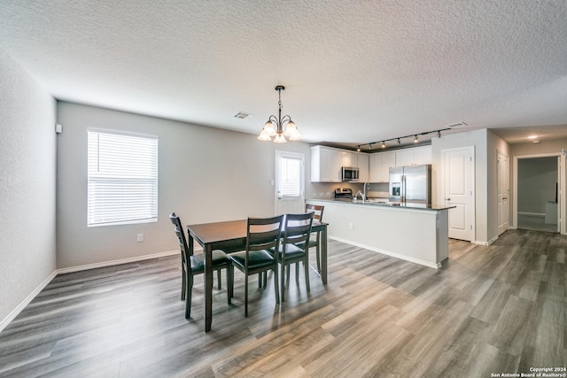 dining room featuring a textured ceiling, dark hardwood / wood-style floors, sink, and an inviting chandelier