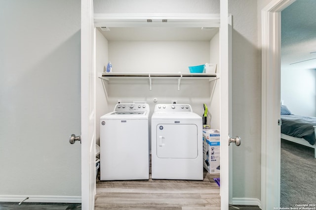 washroom with washing machine and clothes dryer and light hardwood / wood-style floors