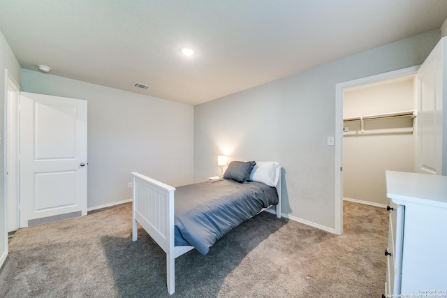 carpeted bedroom featuring a walk in closet and a closet