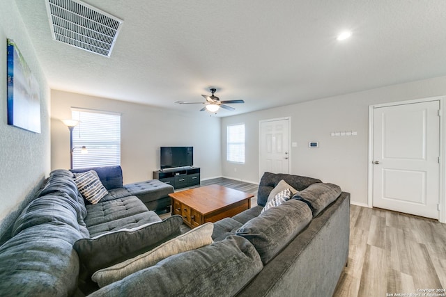 living room with ceiling fan, light hardwood / wood-style floors, and a textured ceiling