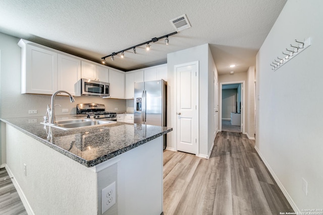 kitchen with white cabinets, light hardwood / wood-style floors, kitchen peninsula, and appliances with stainless steel finishes